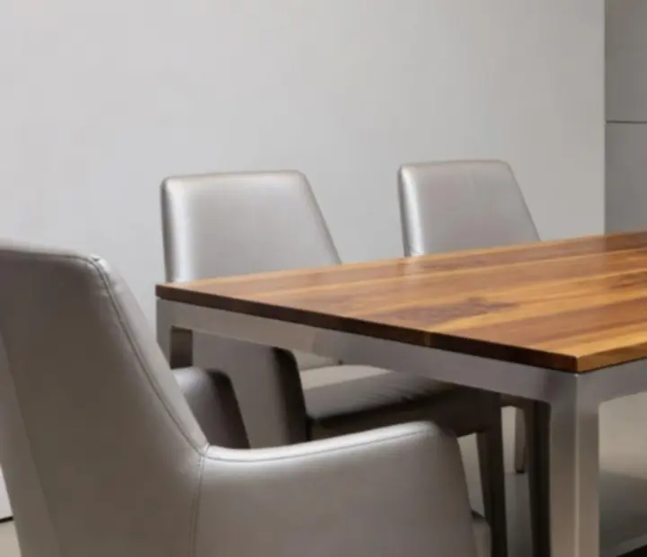 Rich natural wood and brushed steel card tables with bespoke chairs under gentle ambient lighting